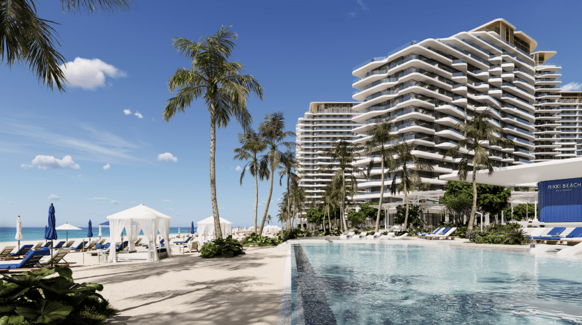 Un complexe luxueux en bord de mer avec une grande piscine, entouré de palmiers et d'immeubles modernes de grande hauteur sous un ciel bleu clair, parfait pour investir à Dubaï.