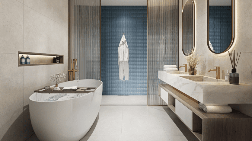 Salle de bains moderne et luxueuse dans une villa de Dubaï comprenant une baignoire autoportante, une double vasque avec des comptoirs en marbre, des miroirs ronds et un mur vertical d'accent en carrelage bleu. Un éclairage chaleureux et des lignes épurées créent une ambiance sereine