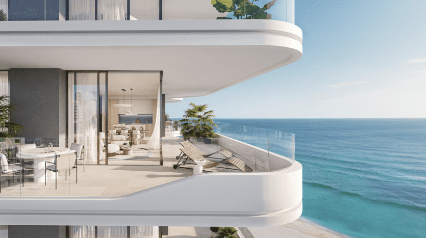 Un appartement moderne et luxueux en bord de mer à Dubaï avec vue sur l'océan, doté d'un mobilier élégant et de portes coulissantes en verre ouvertes menant à un intérieur élégamment décoré.