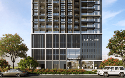 Un moderno rascacielos con una elegante fachada de cristal y metal con el logotipo de Ellington, ajardinado con arbustos y árboles de vivos colores y flanqueado por coches de lujo en la inmobiliaria de Dubai.