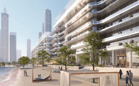 Un moderno complejo frente al mar en un entorno urbano con residencias de varias plantas con balcones, rascacielos al fondo y una playa de arena en primer plano con tumbonas a la sombra y gente paseando por la orilla, que recuerda el animado ambiente del puerto de Dubai.