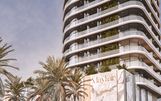 Mayfair Gardens es un edificio moderno de gran altura que presenta una elegante fachada curva y grandes ventanales de vidrio acentuados por líneas blancas horizontales. La estructura presenta plantas verdes en sus balcones y está rodeada de altas palmeras, lo que la convierte en un oasis urbano.