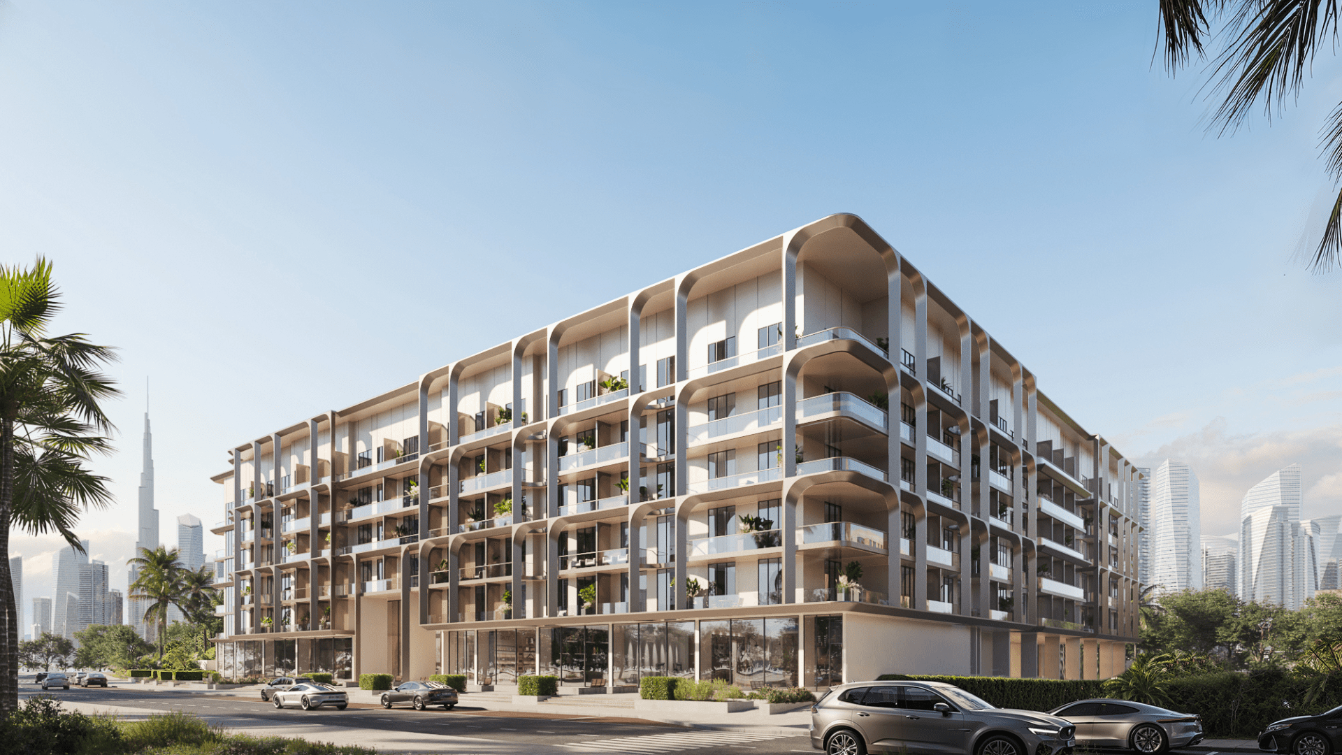 Un moderno edificio de apartamentos de varios pisos con grandes ventanales y balcones, rodeado de palmeras, que recuerda al One Beverly Dubai. Frente a él hay varios coches aparcados en la calle y al fondo, bajo un cielo azul, se ve el horizonte de la ciudad con rascacielos.