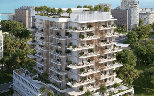 Un moderno edificio de apartamentos de varias plantas rodeado de árboles y con grandes balcones verdes se alza orgulloso cerca de Sunset Bay. La estructura permite vislumbrar el océano al fondo, en armonía con los demás edificios vecinos a lo largo del tranquilo paseo marítimo.