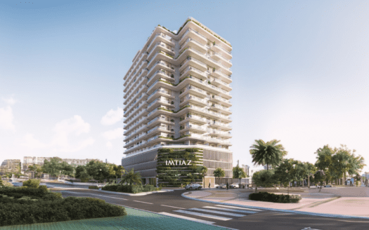 The Cove Edition 3 es un moderno edificio de varias plantas con balcones y exuberantes jardines en su fachada. Las palmeras que lo rodean y el cielo despejado crean un entorno urbano sereno.