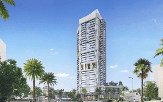 Un moderno rascacielos con un diseño único se eleva desde el cielo azul claro a lo largo del paseo marítimo. Rodeado de palmeras y vegetación, se ven algunos coches en su base, creando un ambiente urbano y tropical a la vez.