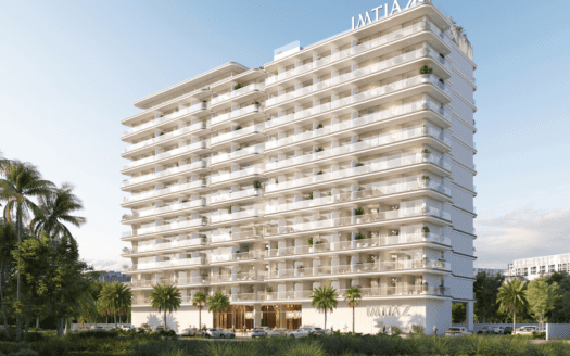 Un moderno bloque de pisos blancos de varias plantas - Cove Edition 6 by Imtiaz - con grandes balcones y palmeras en la fachada destaca sobre un cielo azul despejado. El rótulo "IMTIAZ" corona la parte superior y aparece sobre la entrada principal.