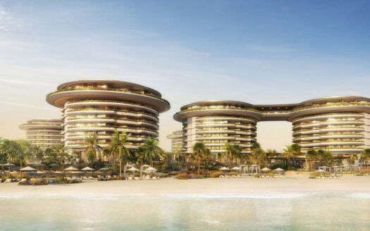 El futurista complejo turístico The Edition está compuesto por edificios circulares de varios pisos rodeados de palmeras y tumbonas en una playa de arena, frente a unas aguas tranquilas y azules bajo un cielo despejado.