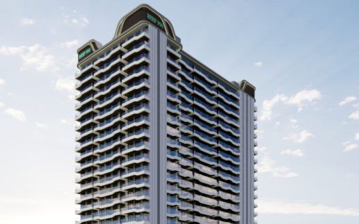 Un grand immeuble moderne, Reef 996, avec de nombreux balcons et baies vitrées, se dresse sur un ciel bleu parsemé de nuages. La structure présente des angles incurvés et des panneaux de signalisation sur le toit.