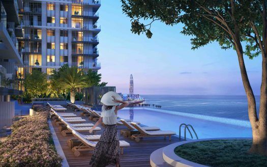 Une femme portant un large chapeau admire la vue sur l'océan depuis une piscine luxueuse avec des chaises longues, entourée d'une verdure luxuriante, au crépuscule. Une jetée s'étend dans la mer en arrière-plan près d'un