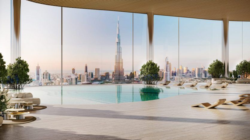 Luxueuse piscine intérieure à débordement surplombant les toits de la ville avec de grands gratte-ciel, dont une tour proéminente, visible à travers une fenêtre panoramique. Des chaises longues et une décoration moderne rehaussent l'ambiance sereine, parfaite pour votre