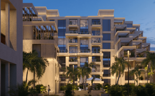 L'immeuble moderne à plusieurs étages d'Arisha dispose de grandes baies vitrées et de terrasses. Entouré de palmiers et d'une végétation luxuriante au crépuscule, il dégage une atmosphère accueillante avec son éclairage chaleureux.