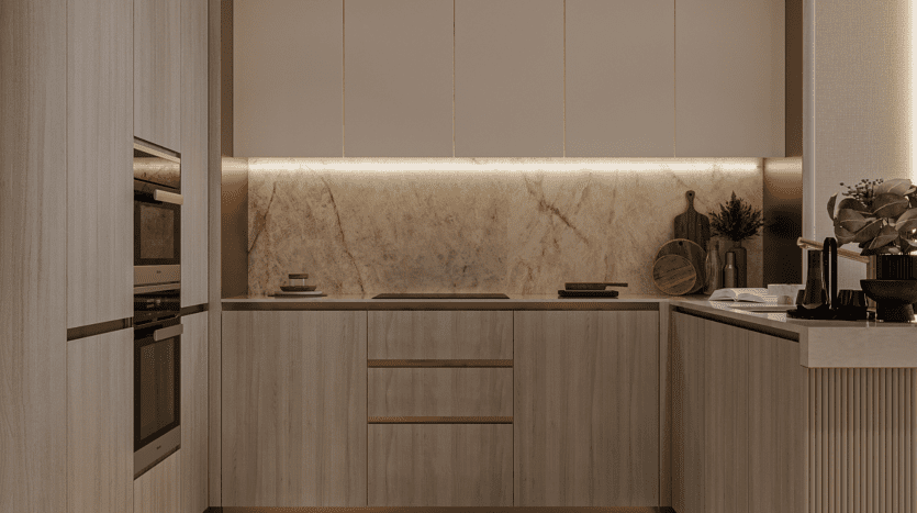 Cuisine moderne avec placards en bois clair, crédence en marbre et four encastré. L'éclairage sous les placards renforce l'aspect épuré et minimaliste, tandis que les touches de ciel fleuri apportent une touche de fraîcheur aux plans de travail, avec planches à découper, plante et accessoires essentiels.