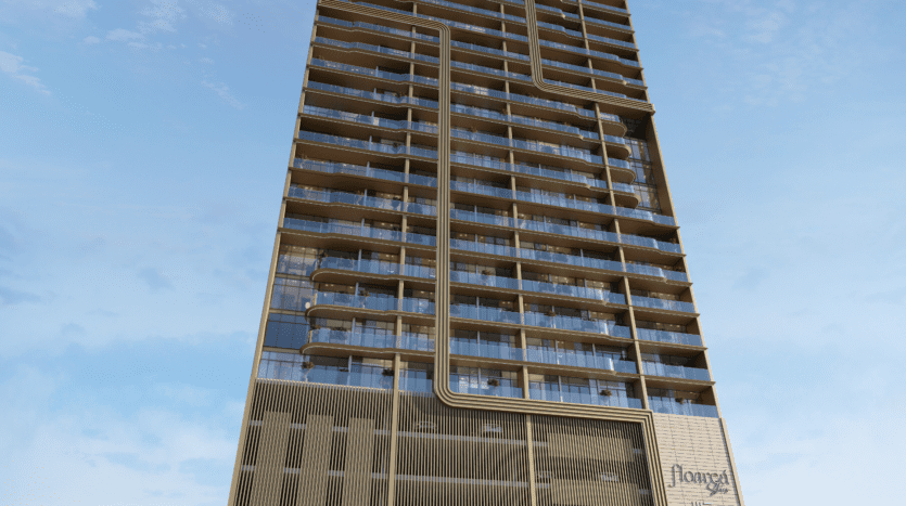 Un immeuble moderne de grande hauteur avec des balcons en verre et des lignes verticales et horizontales distinctives s'élève dans le ciel de la zone florale, vu sous un angle bas contre un ciel bleu avec des nuages épars.