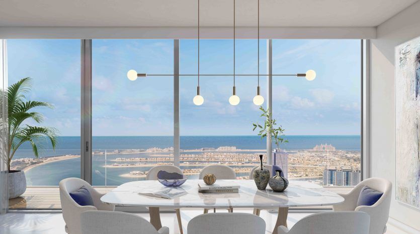 Salle à manger moderne avec une grande fenêtre offrant une vue panoramique sur la plage, une table dressée pour quatre et un élégant luminaire suspendu. Décoration minimaliste sur le thème côtier.