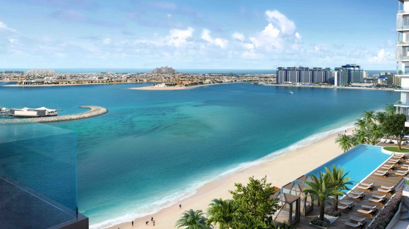 Vue aérienne d'un front de mer luxueux avec des eaux turquoise claires, une plage de sable fin et un immeuble moderne de grande hauteur donnant sur une piscine et une promenade sur la plage de Dubaï.