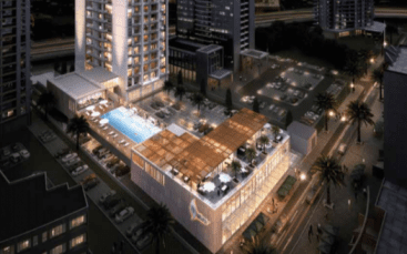 Vue aérienne nocturne du Studio One dans la marina de Dubaï, avec une piscine bien éclairée entourée de grands immeubles résidentiels et de parkings adjacents.