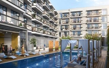 Immeubles d'appartements modernes du Panthéon Elysée 2 avec balcons donnant sur une piscine commune dotée de chaises longues, de cabanes et de résidents profitant de la journée ensoleillée.
