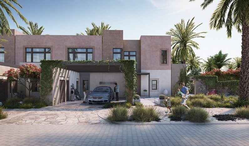 Résidence moderne de deux étages avec une finition en stuc beige, entourée de palmiers luxuriants et d'arbustes à fleurs. Comprend une allée pavée avec une voiture garée et une personne lavant une autre voiture al jure