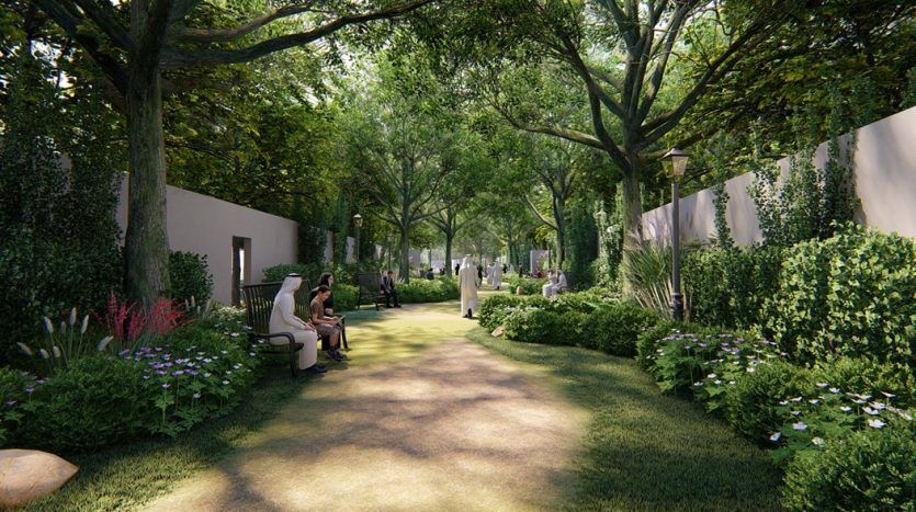 Une allée de jardin sereine bordée d'arbres luxuriants, de plantes à fleurs et de haies soigneusement taillées. Plusieurs bancs sont placés le long du chemin où les gens peuvent s'asseoir et profiter du paysage en plein air.
