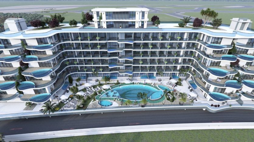 Vue aérienne d'un complexe moderne à plusieurs étages avec balcons et piscines, entouré des espaces paysagers du parc Samana et à proximité d'une route.