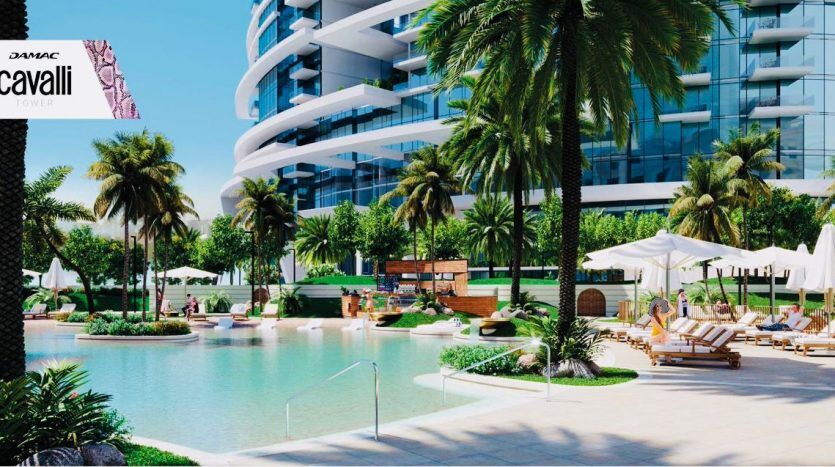An extravagant outdoor pool area at DAMAC's Roberto Cavalli tower in Dubai, with lush green palm trees, several sun loungers, modern buildings and a serene water feature.