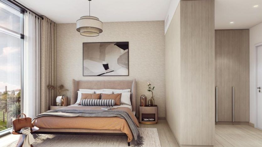 Une chambre moderne dans Harrington House comprenant un grand lit avec une literie neutre, des meubles en bois, une œuvre d'art abstraite encadrée au-dessus du lit et une grande fenêtre laissant entrer beaucoup de lumière naturelle.