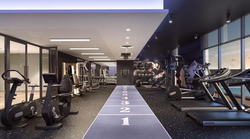 Un intérieur de salle de sport Harrington House avec divers équipements d'exercice, notamment des tapis roulants, des vélos stationnaires et des poids. L'étage présente une piste centrale avec des voies numérotées.