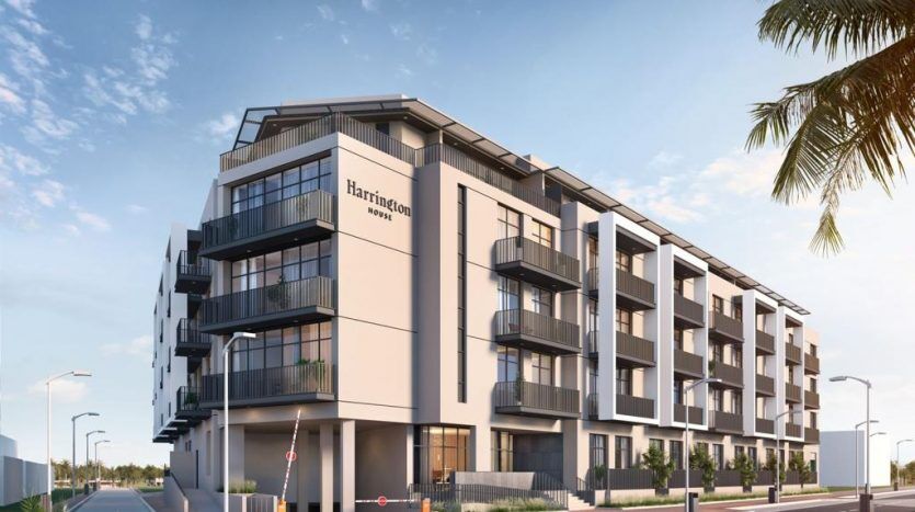 Un immeuble résidentiel moderne de plusieurs étages avec balcons, nommé « Harrington House » sur la façade. Le bâtiment se trouve dans une rue ensoleillée avec un environnement soigneusement aménagé.