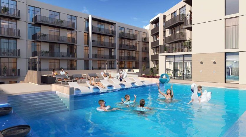 Une piscine extérieure animée du complexe d'appartements Harrington House, où les gens profitent du soleil, nagent et flottent sur des jouets gonflables. Les bâtiments disposent de balcons donnant sur la piscine.