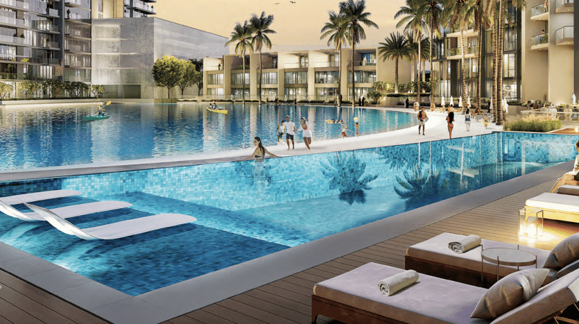 Espace luxueux au bord de la piscine dans un complexe moderne de Dubaï, doté d'une vaste piscine, de chaises longues et de résidents profitant de diverses activités sous un coucher de soleil éclatant avec vue sur le lagon.