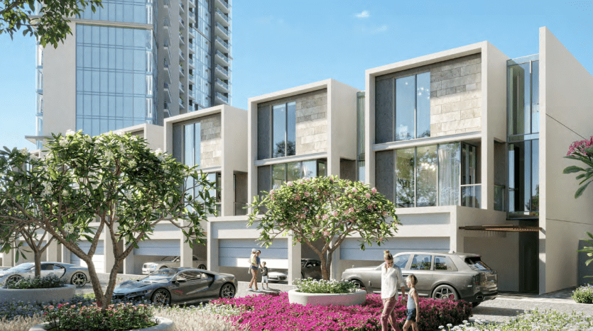 Une rue résidentielle moderne avec des maisons de ville élégantes à plusieurs étages, des jardins luxuriants et des piétons. Grand bâtiment en arrière-plan sous un ciel bleu clair à Dubaï.