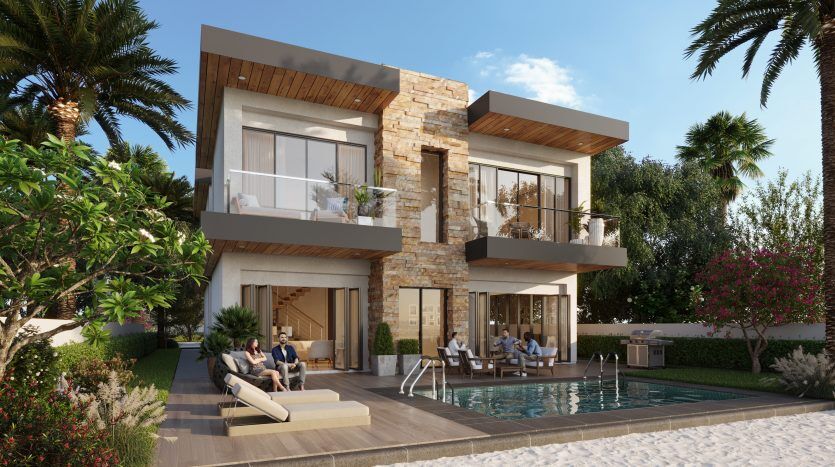 Luxueuse maison de deux étages avec des accents de pierre dans les lagons de Damac sur la Costa Brava, dotée de grandes fenêtres en verre et de balcons donnant sur une piscine, où un groupe de personnes se détendent et discutent.