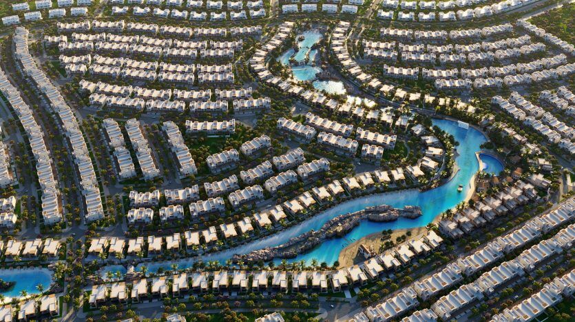 Vue aérienne d'un quartier résidentiel de Dubaï avec des voies navigables artificielles sinueuses, des rangées de maisons blanches similaires, une verdure luxuriante et de multiples piscines éclairées par la lumière du soleil.