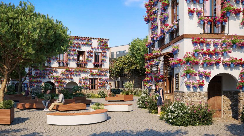 Une place animée où les gens se détendent et se promènent. Les bâtiments sont ornés de fleurs colorées et la place présente des allées en pierre, des bancs et une verdure luxuriante rappelant les lagons de Damac Costa Br.