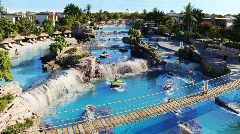 Une scène de parc aquatique animée avec une grande cascade artificielle, un pont de corde avec passage de visiteurs et des personnes pratiquant diverses activités nautiques dans un cadre tropical entouré d'une végétation luxuriante à proximité d'une villa haut de gamme à Dubaï.