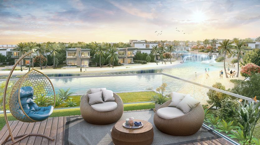 Un balcon luxueux avec vue sur une villa à Dubaï, avec des gens profitant d'une grande piscine sereine, d'une cascade au loin, d'une verdure luxuriante et de chaises longues modernes sous un ciel bleu clair.