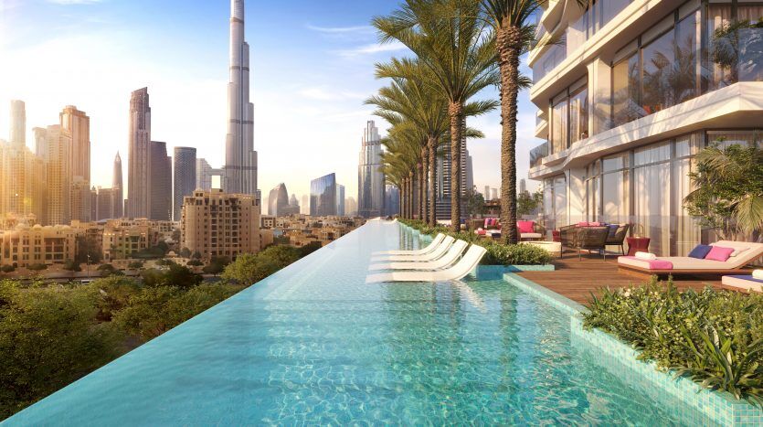 Luxueuse piscine à débordement sur le toit surplombant un paysage urbain moderne avec des gratte-ciel, dont une tour particulièrement haute, entourée de palmiers luxuriants et de coins salons confortables au coucher du soleil, idéale pour ceux qui cherchent à investir