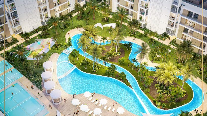 Vue aérienne d'un luxueux complexe hôtelier de Dubaï comprenant une vaste piscine sinueuse entourée de plantes tropicales, de palmiers et de bâtiments blancs modernes, où les gens profitent de diverses activités au bord de la piscine.