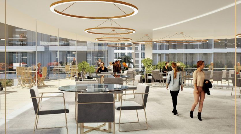 Intérieur de restaurant moderne doté d'un mobilier élégant et d'un éclairage circulaire au plafond, avec des gens conversant dans un cadre spacieux et éclairé naturellement qui rappelle une luxueuse villa à Dubaï.