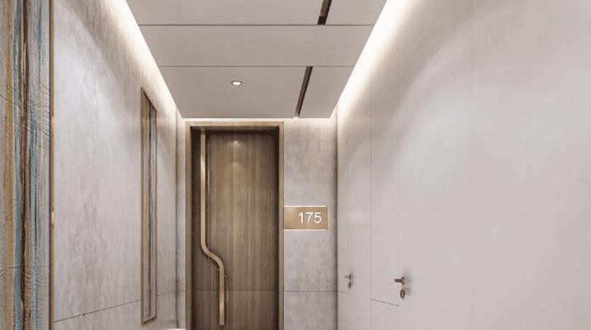 Elegantly designed modern hallway with light gray walls, embellished with a textured panel and a sleek, elegant light fixture. A wooden door bears the number 175 at the end of the hallway in this