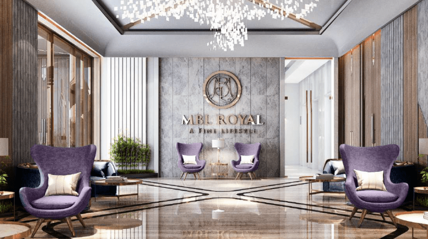 Luxurious lobby with marble floors, large royal mbl logo on wall, plush purple chairs and elegant chandelier close to a Dubai apartment.