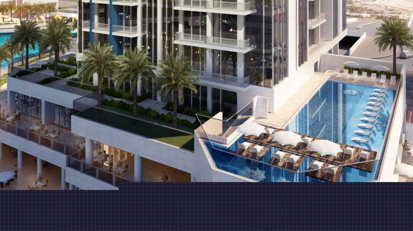 Aerial view of a modern beachfront complex in Dubai, featuring a rooftop infinity pool surrounded by palm trees and sun loungers, overlooking a sandy beach.