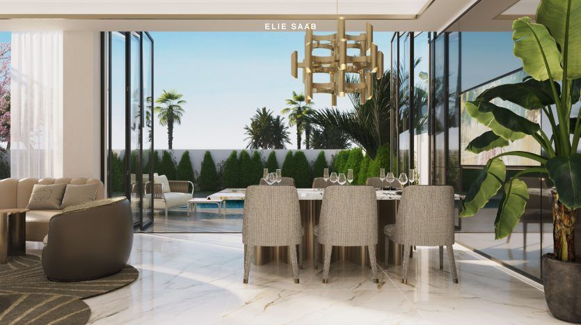 Coin repas luxueux avec un mur transparent donnant sur une piscine et des palmiers. Comprend un lustre moderne, une table élégante pour quatre personnes et des sièges luxueux dans une villa de Dubaï. Marqué "Elie