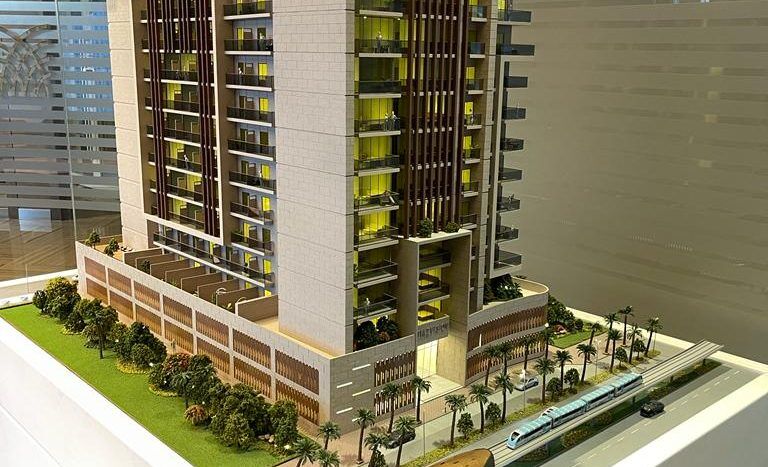 Un modèle architectural détaillé d'une villa moderne à Dubaï affiché sur une plate-forme, comprenant des espaces verts, des arbres, une piscine et des véhicules garés.