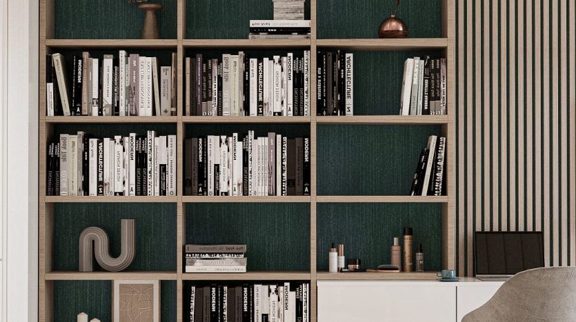 Un salon moderne et élégant dans une villa de Dubaï comprenant une grande bibliothèque bleu sarcelle et en bois remplie de livres et d'objets de décoration, un bureau minimaliste et un fauteuil confortable à côté d'une table centrale rustique.