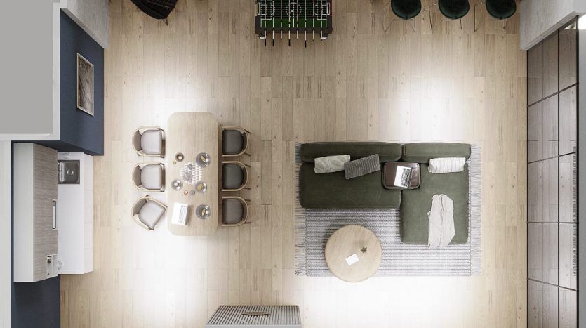 Vue plongeante d'un appartement moderne à Dubaï, comprenant un salon décloisonné avec un canapé vert, un coin repas, une cuisine compacte et un balcon confortable avec des plantes.