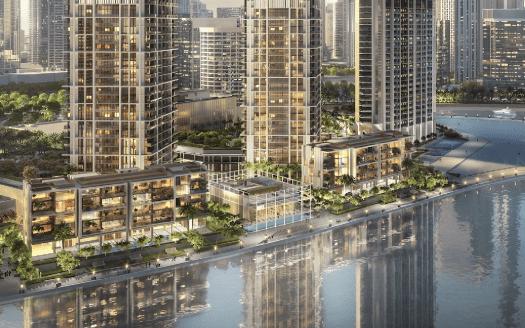 Veduta aerea di un moderno complesso residenziale sul lungomare con diversi grattacieli, spazi verdi lussureggianti e facciate illuminate al crepuscolo in un contesto urbano a Dubai.