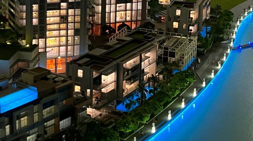 Vue aérienne d'un paysage urbain moderne la nuit, avec des bâtiments illuminés au bord d'une rivière bleue éclatante, avec une verdure luxuriante le long de ses rives à Dubaï.