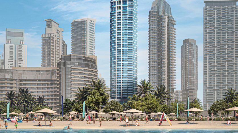 A lively beach scene in Dubai with people enjoying the sun, sand and water, against a backdrop of modern high-rise buildings under a clear blue sky.